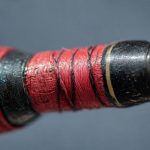 Close-up of fishing rod tip showing crack repair with thread wrapping and epoxy coating