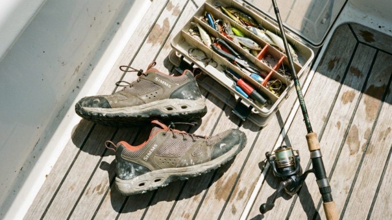 Quick dry fishing shoes sitting on a boat deck next to tackle gear.