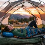 Hiker relaxing inside a tent using an affordable camping pillow.