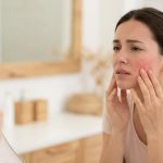 Woman gently massaging sore cheeks after a buccal massage spa treatment
